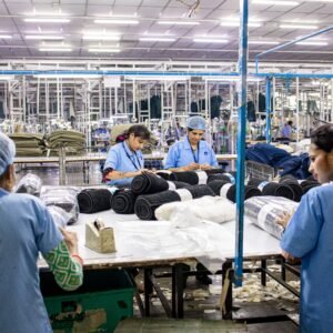 Blue-collar workers organize textiles in a busy factory setting.