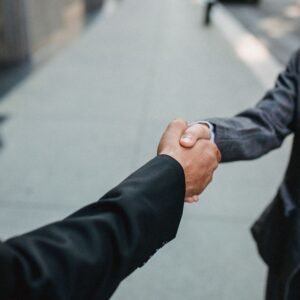 Close-up of two businessmen shaking hands outside, symbolizing partnership and agreement.