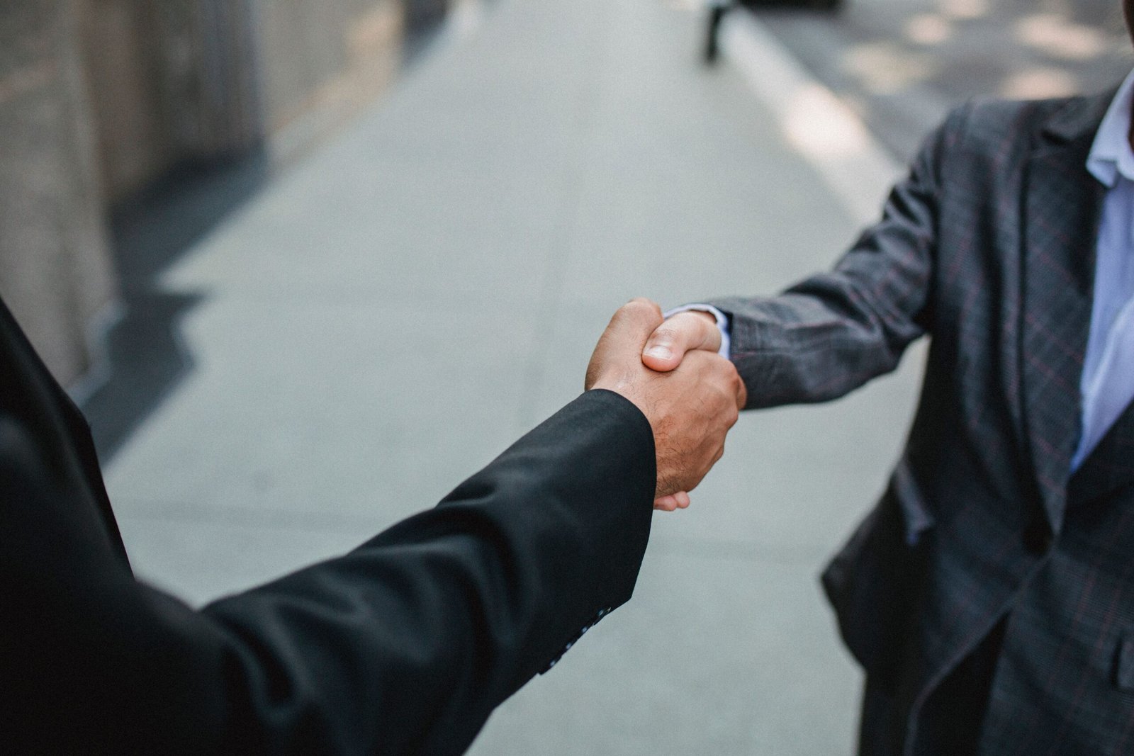 pexels-photo-4963359-4963359 Close-up of two businessmen shaking hands outside, symbolizing partnership and agreement.